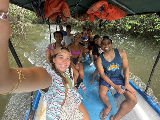 Small group travel participants smiling on a river boat during a crocodile tour in Tamarindo Costa Rica.