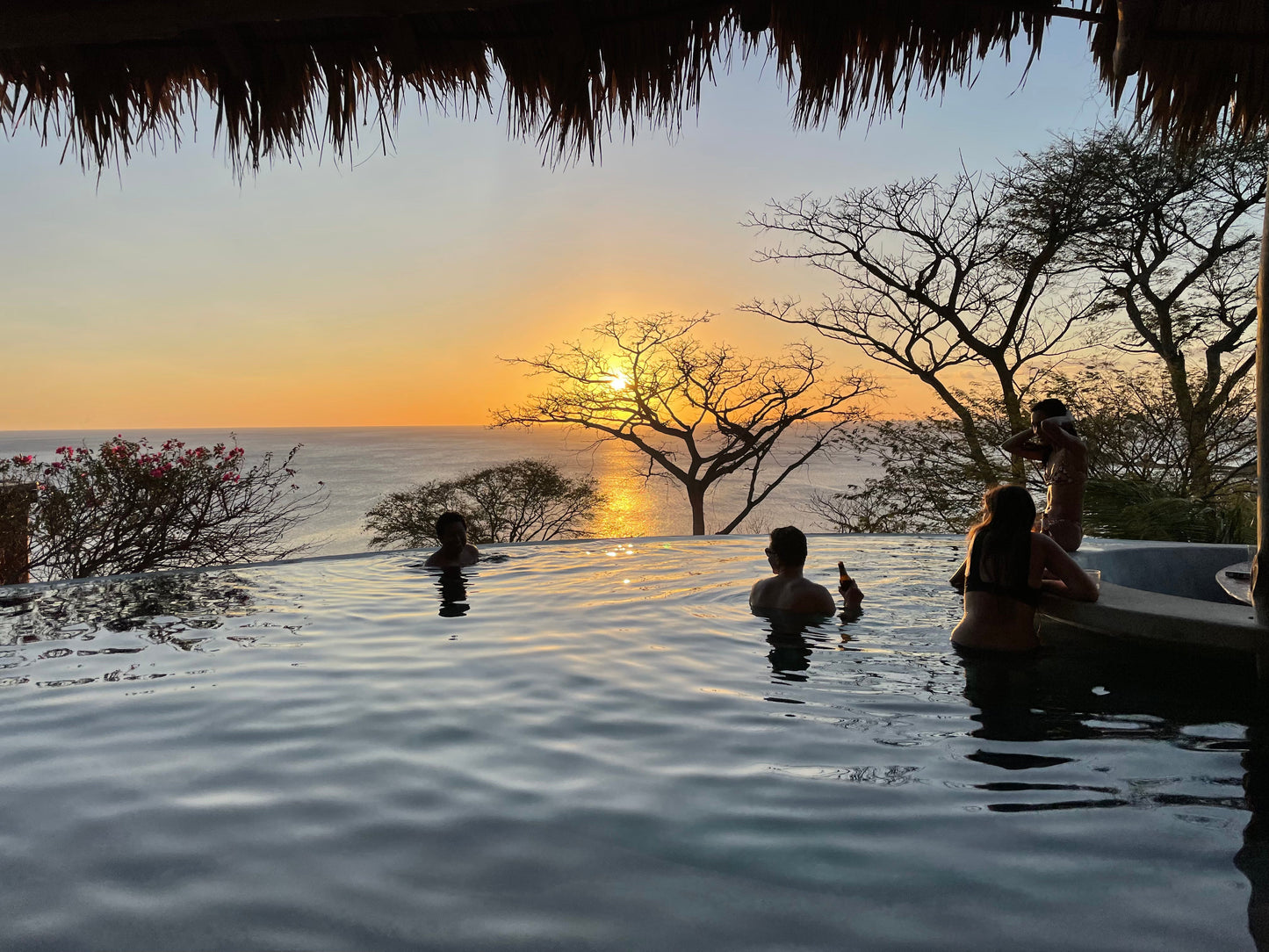 Small group travel participants relaxing in an oceanside pool during sunset in San Juan Del Sur.