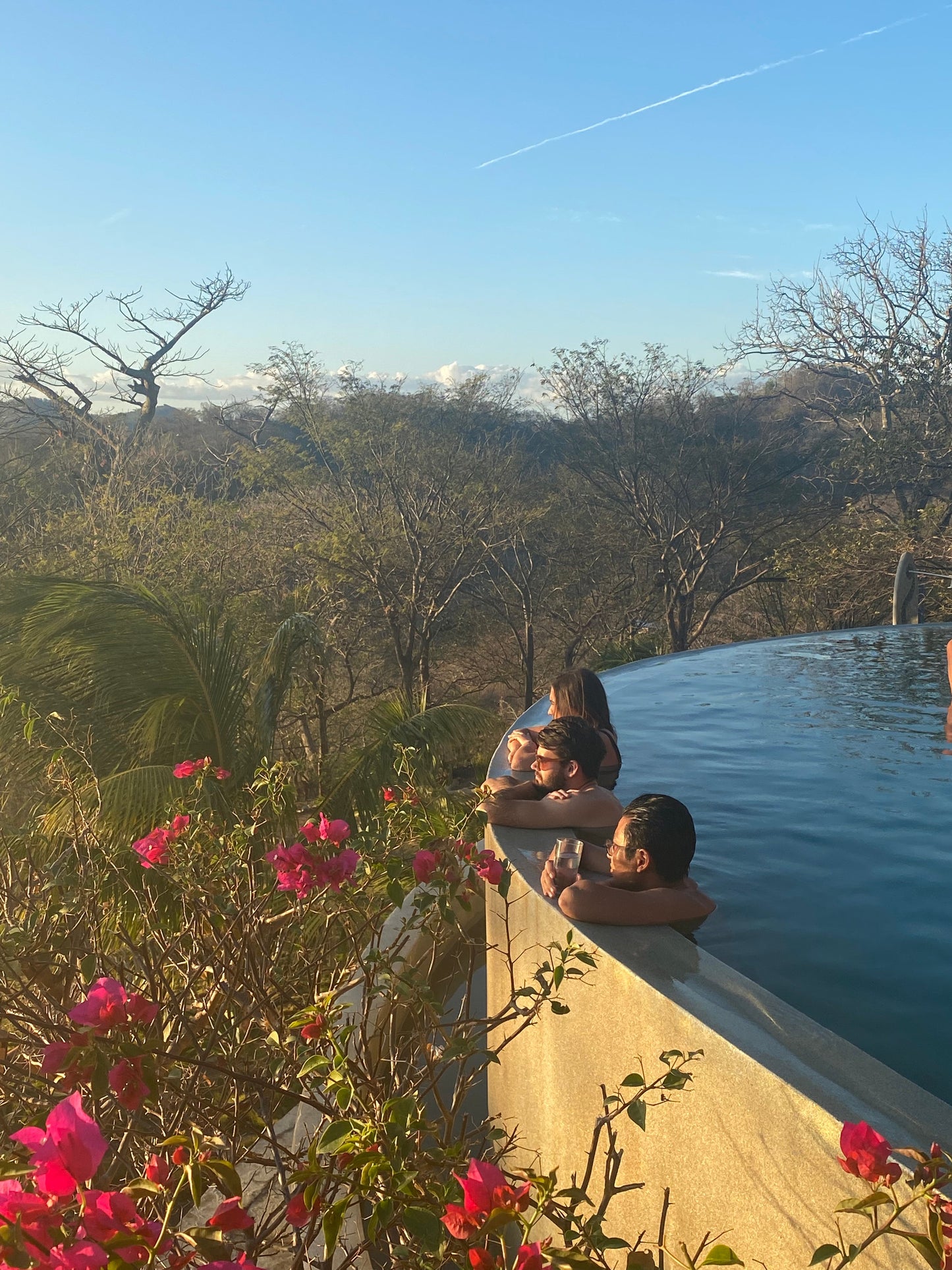 Three trip participants hanging over a pool ledge near pink flowers in San Juan Del Sur.
