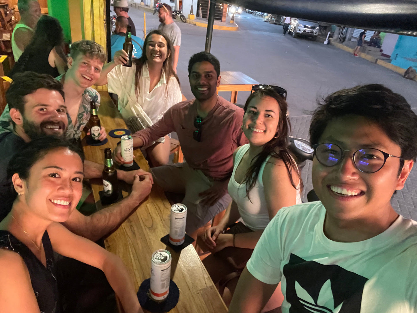Small group travel participants having drinks outside on a wooden table in San Juan Del Sur.