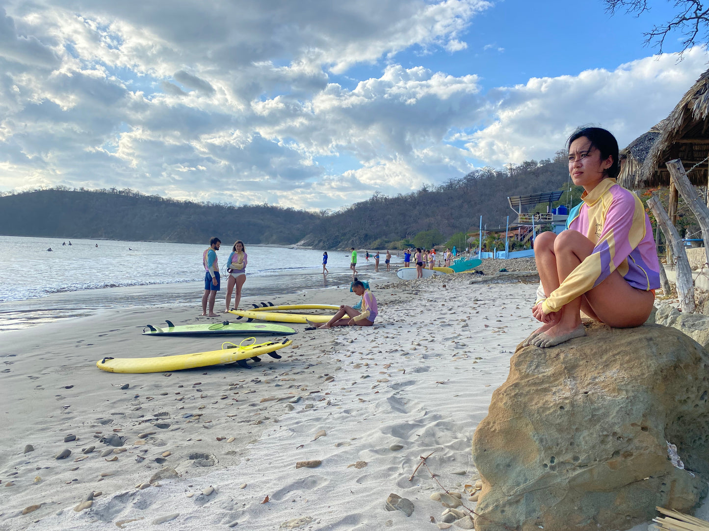 Trip participants along the San Juan Del Sur beach talking near their surfboards.