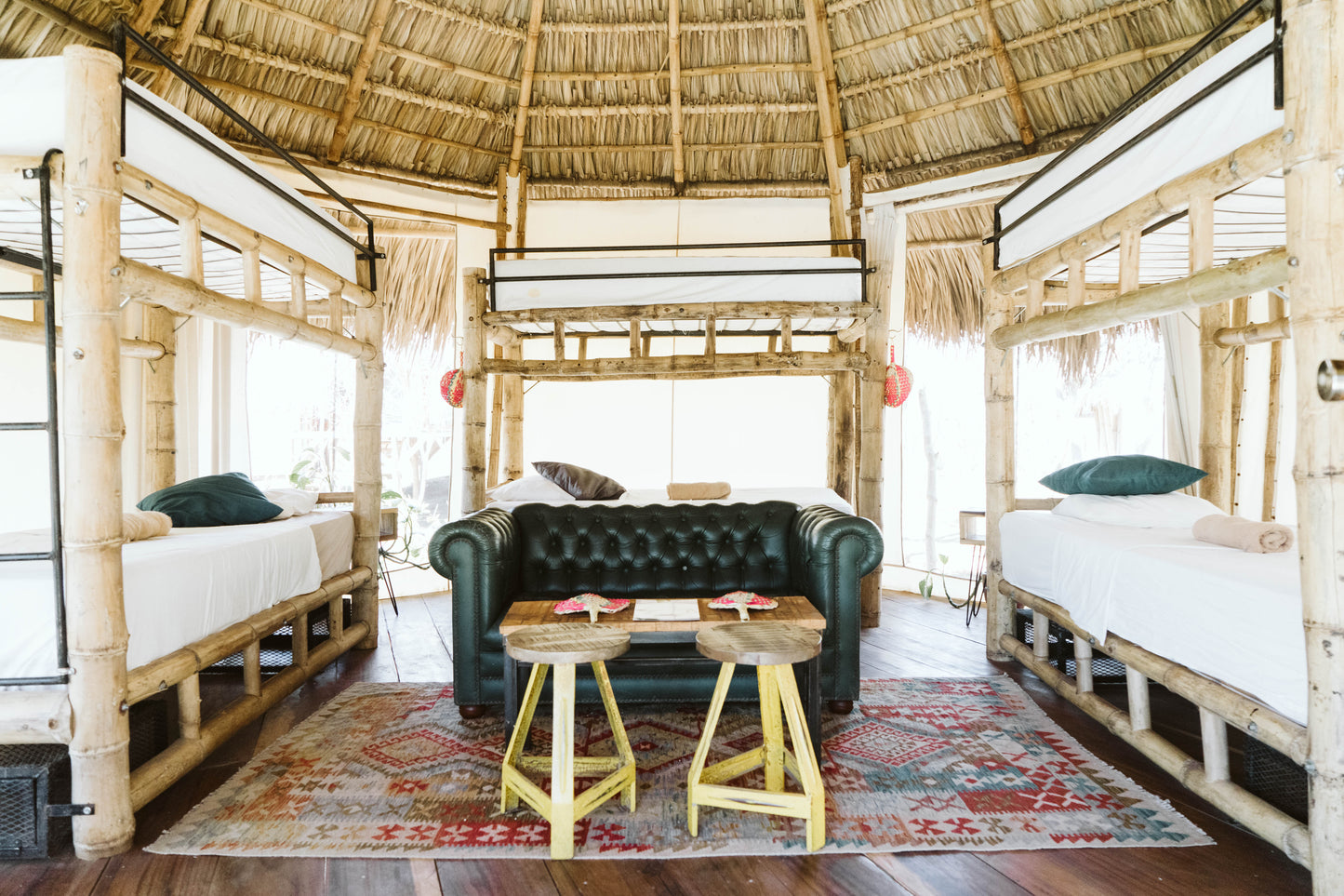 Dreamsea Surf canopy room with six bunk beds and a black sofa in San Juan Del Sur.