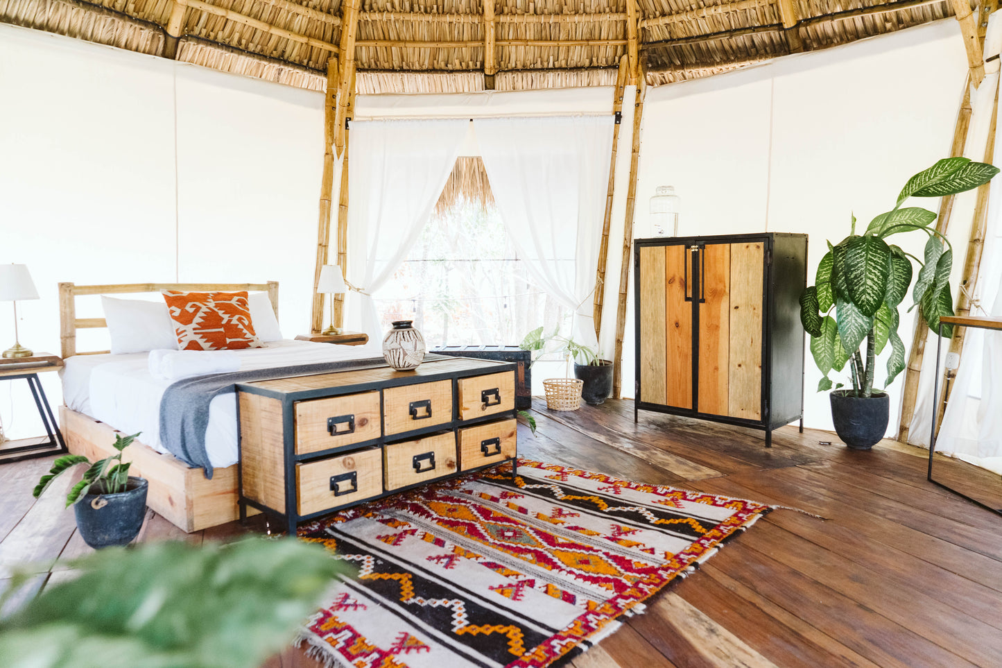 Inside a Dreamsea Surf single canopy with a large bed, rug, plants, and dresser in San Juan Del Sur.