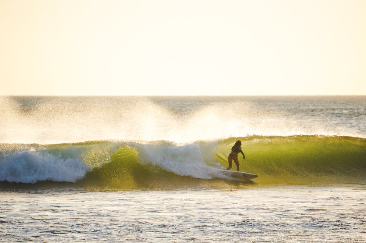 Girl surfing a wave in San Juan Del Sur during small group travel.