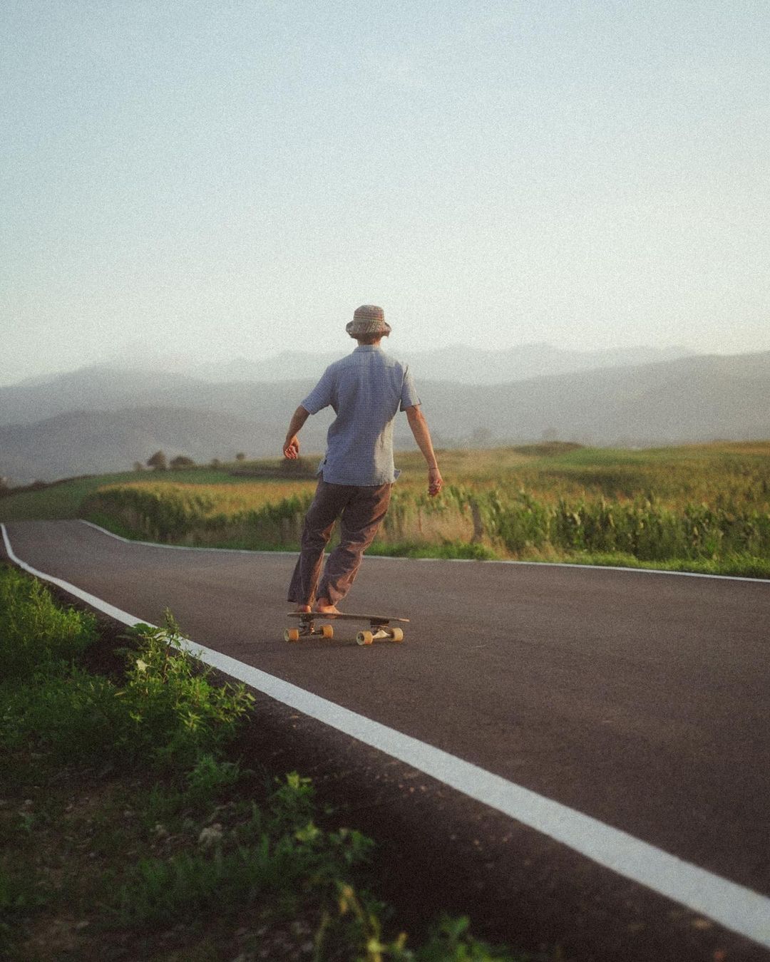 Guy longboarding barefoot on a paved road in Cantabria during small group travel.
