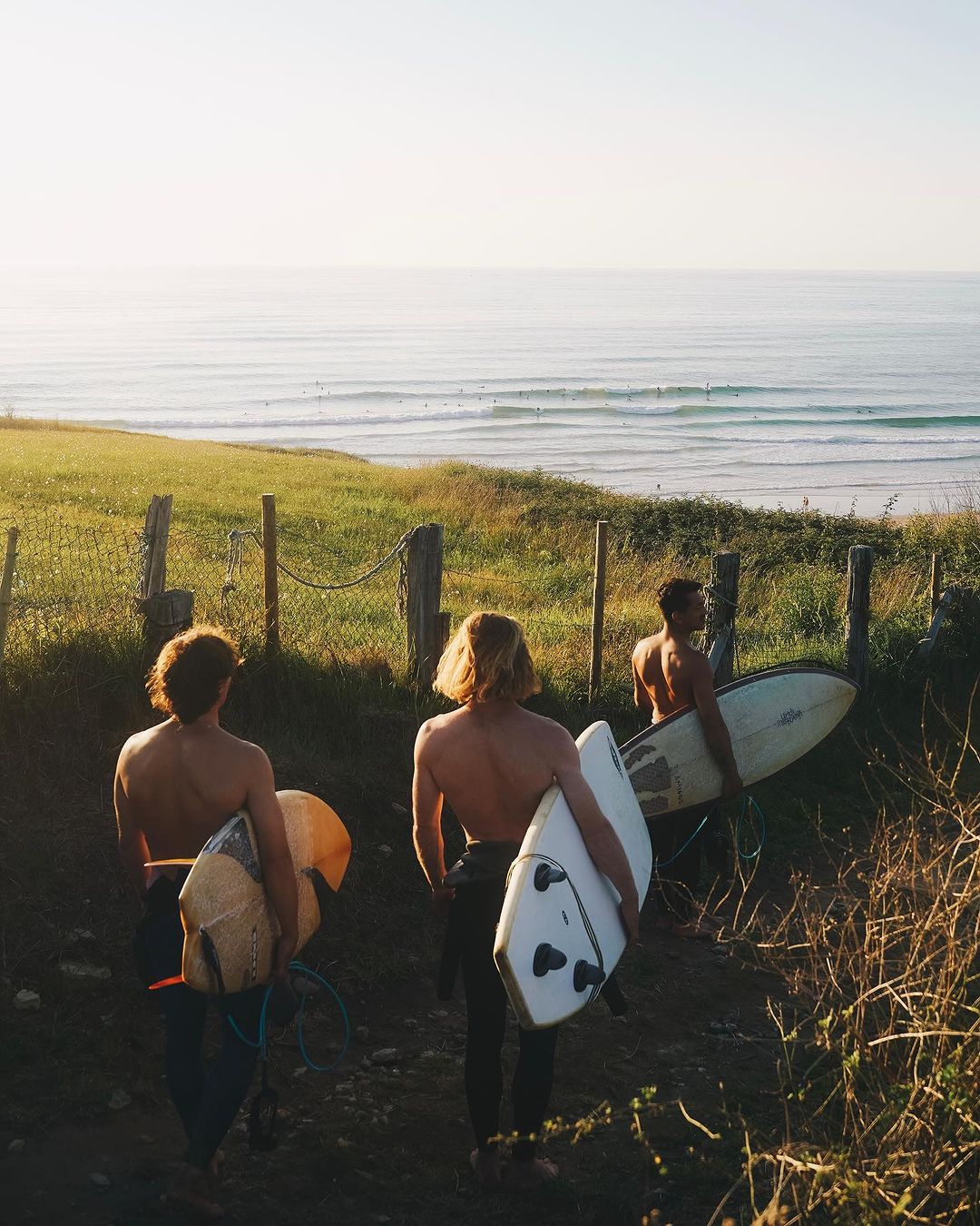 Three surfers heading down to the beach for their surfing lessons in Cantabria.