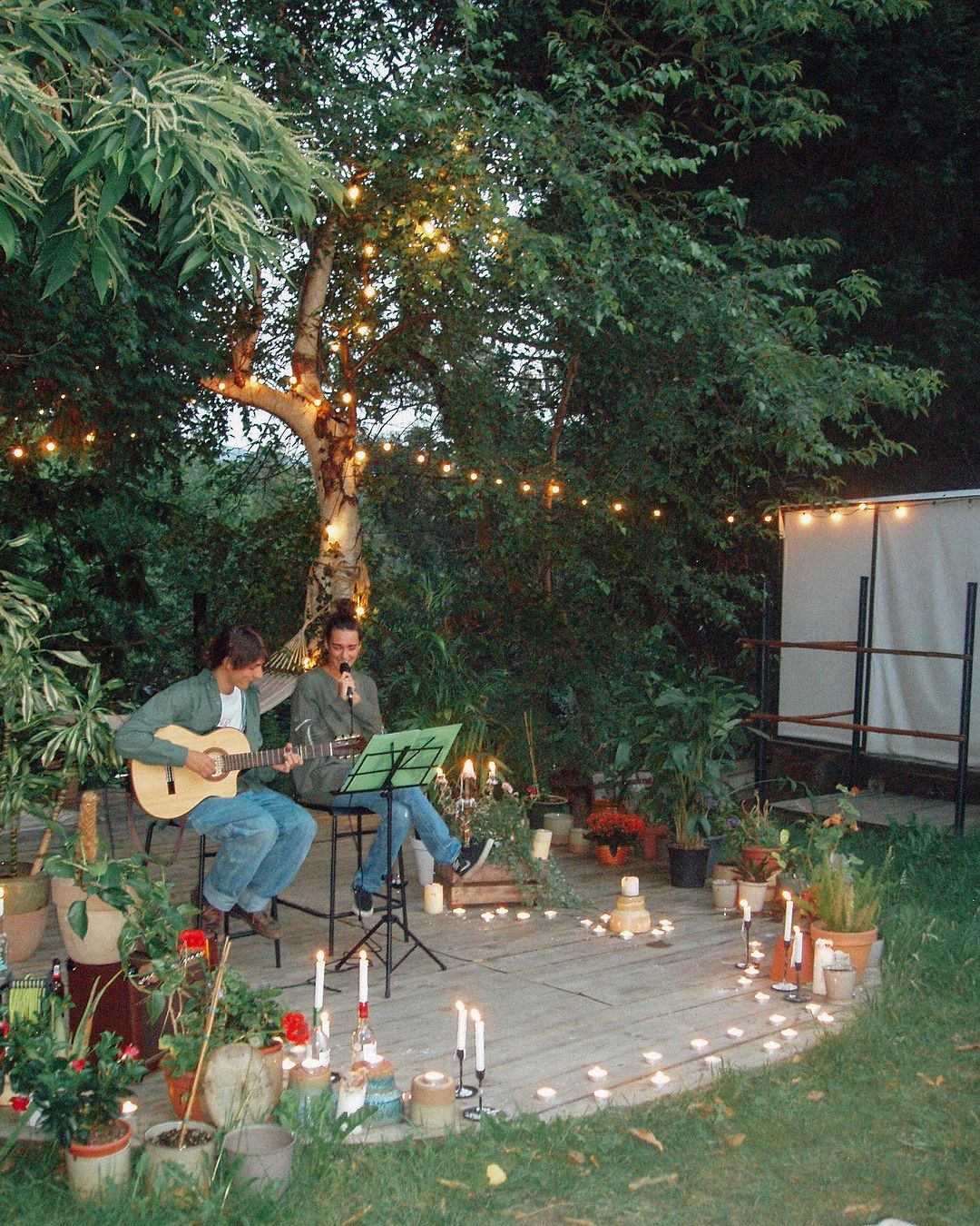 Guitar player and singer surrounded by candles in the outdoor space of Amigos Surf camp in Cantabria.