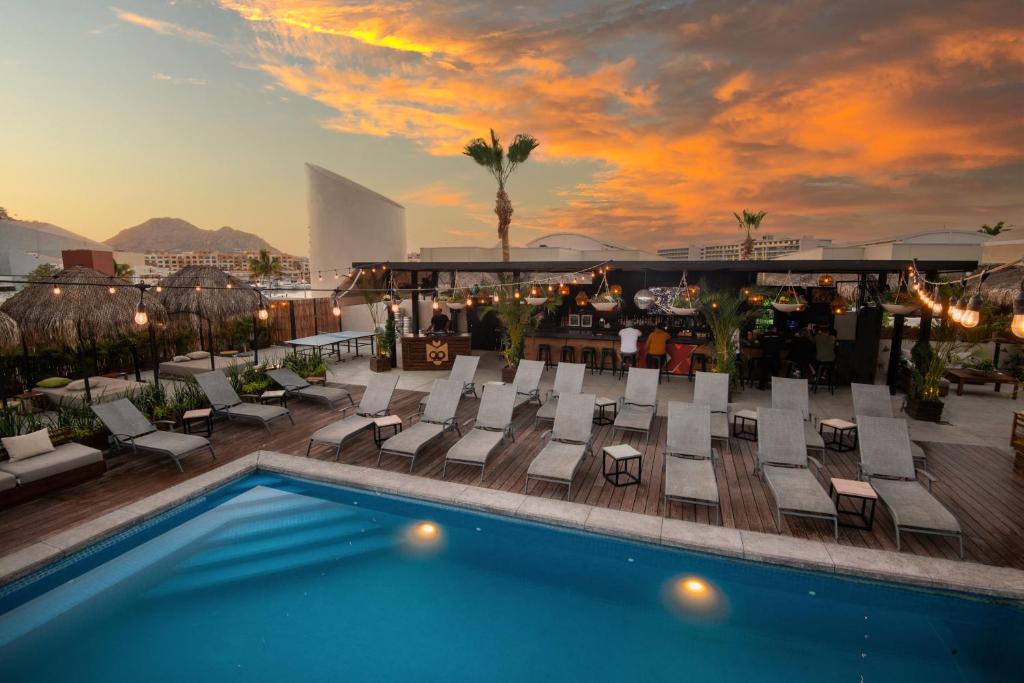 Sun setting over the outdoor pool and lounge area at the Mayan Monkeys hostel in Los Cabos.