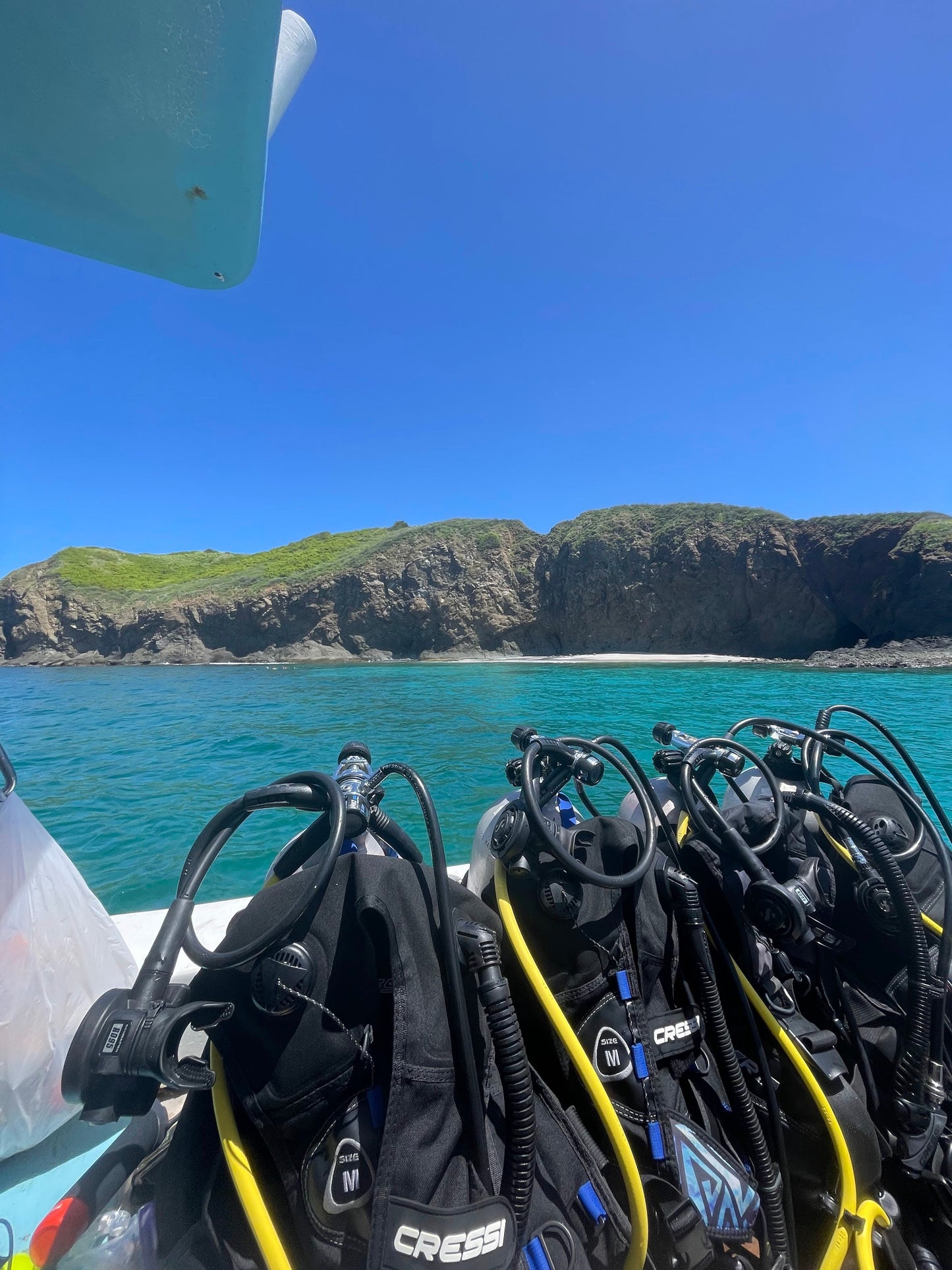Scuba diving gear at the edge of a boat overlooking the turquoise water in Islas Catalinas.