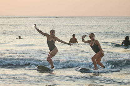 Two girls posing for the camera while surfing in Costa Rica during a small group trip.