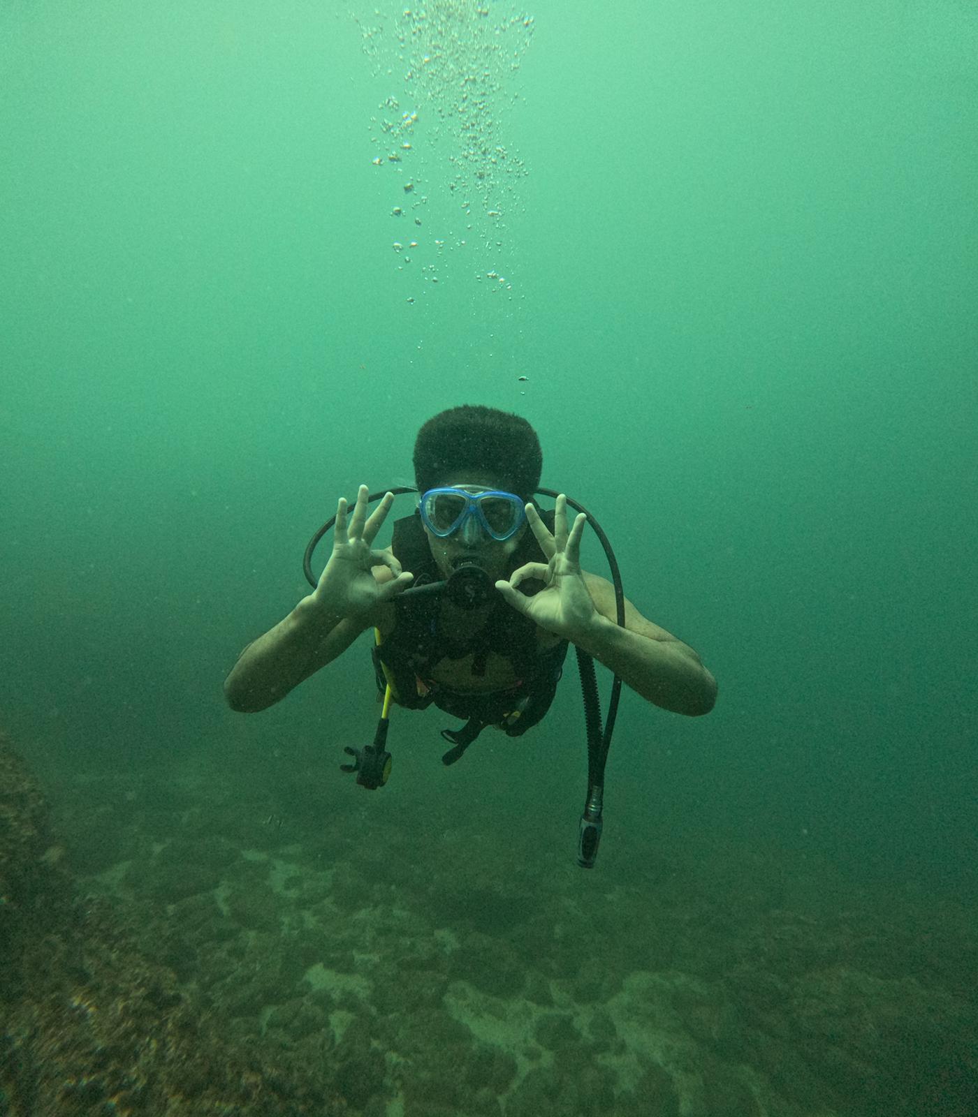 Small group travel participants holding the OK sign underwater while scuba diving in Costa Rica.