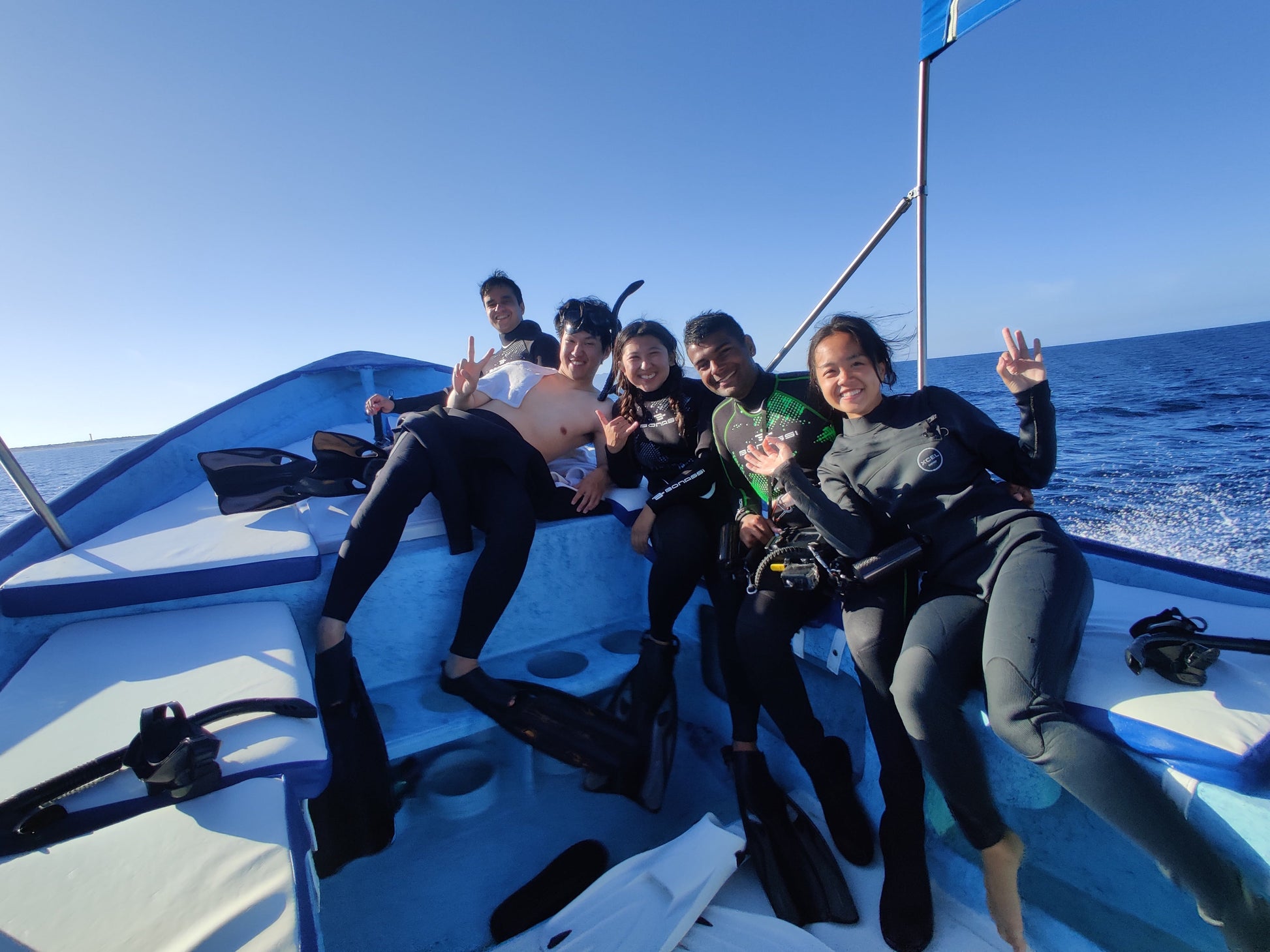 Small group travel participants smiling on the boat after completing a scuba diving session in Los Cabos.