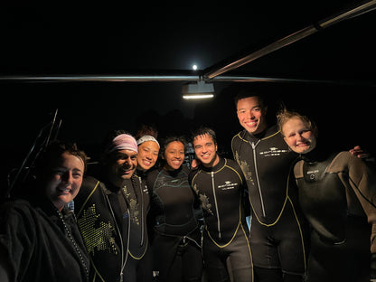Small group travel participants smiling on the boat after finishing their scuba diving lesson in Los Cabos Mexico.