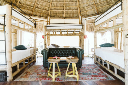 Dreamsea Surf canopy room with six bunk beds and a black sofa in San Juan Del Sur.