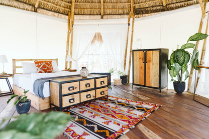 Inside a Dreamsea Surf single canopy with a large bed, rug, plants, and dresser in San Juan Del Sur.