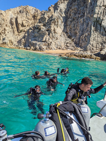 Scuba divers floating in the ocean near a boat in Los Cabos during group excursion.