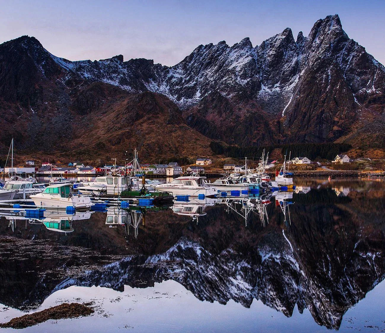 Reflection of the mountains under boats in the Ballstad harbor in Norway during a group trip.