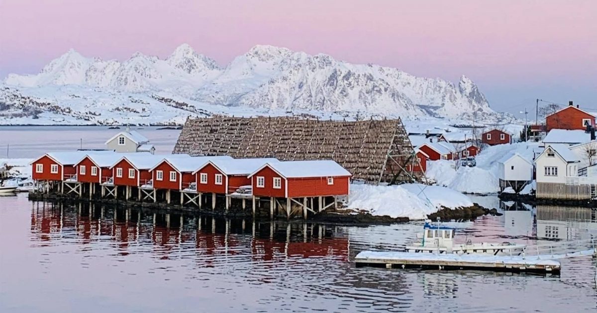 Landscape view of the Lofoten Norway accommodation over the lake and surrounded by snowy mountains.