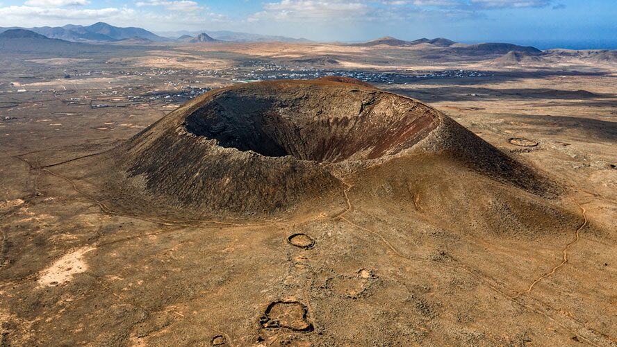 Calderon Hondo crater in Fuerteventura on a partly cloudy day during a group excursion.