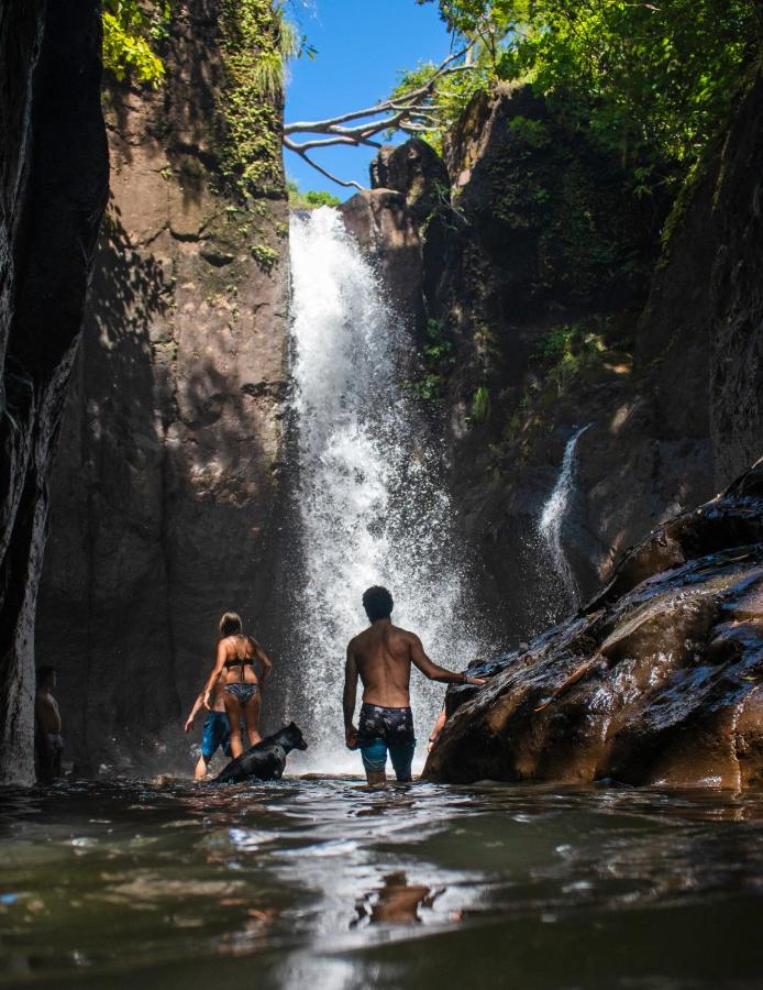 Group participants standing at the bottom of a waterfall on a trip excursion in El Salvador.