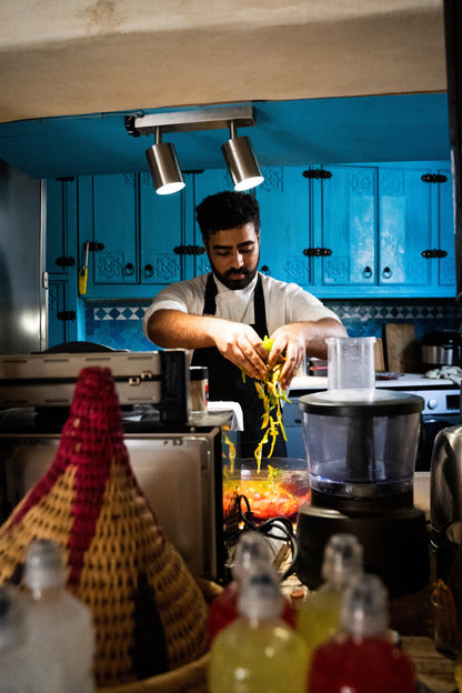 Chef mixing ingredients in front of blue cupboards in Taghazout.