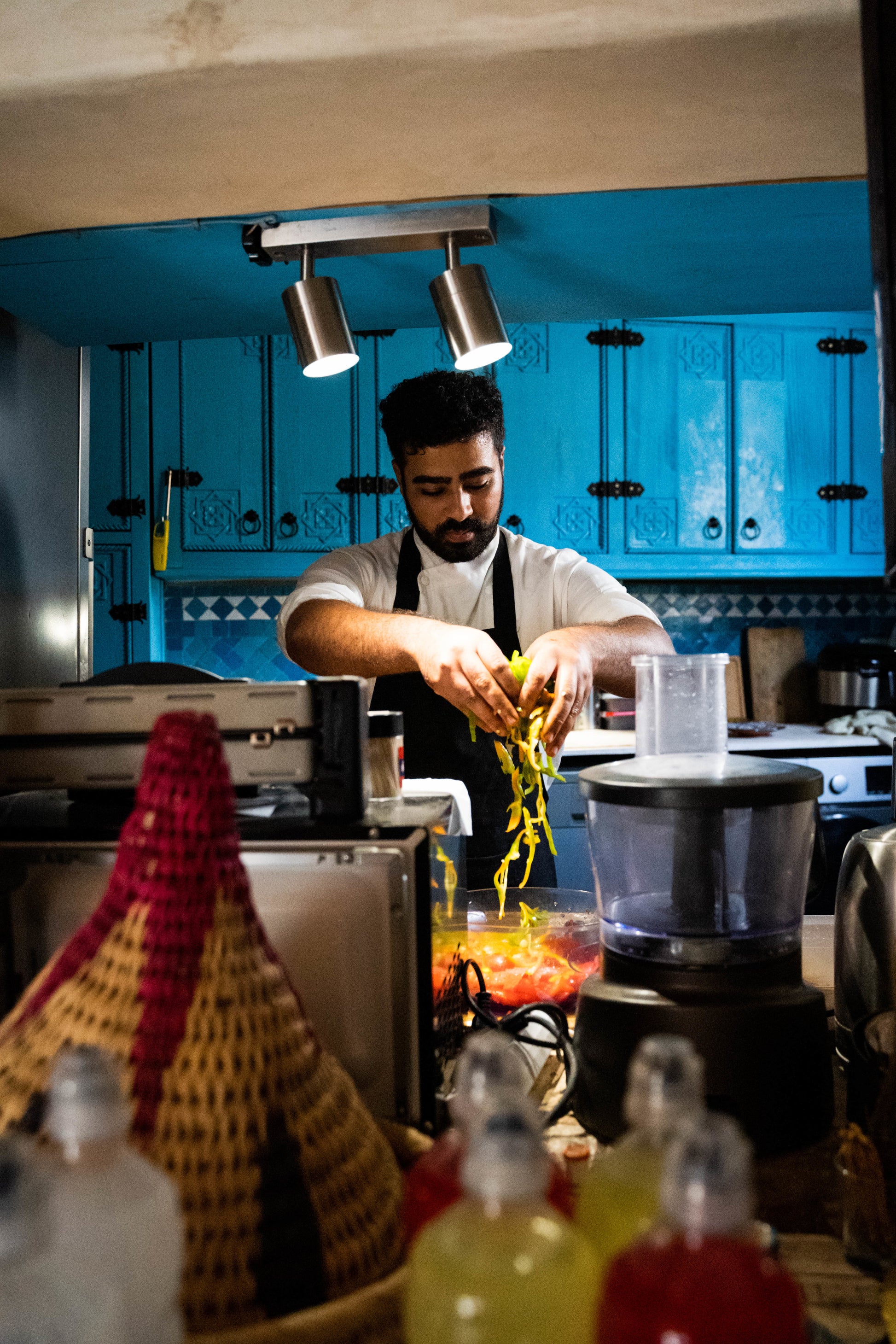 Chef mixing ingredients in front of blue cupboards in Taghazout for a small group trip.