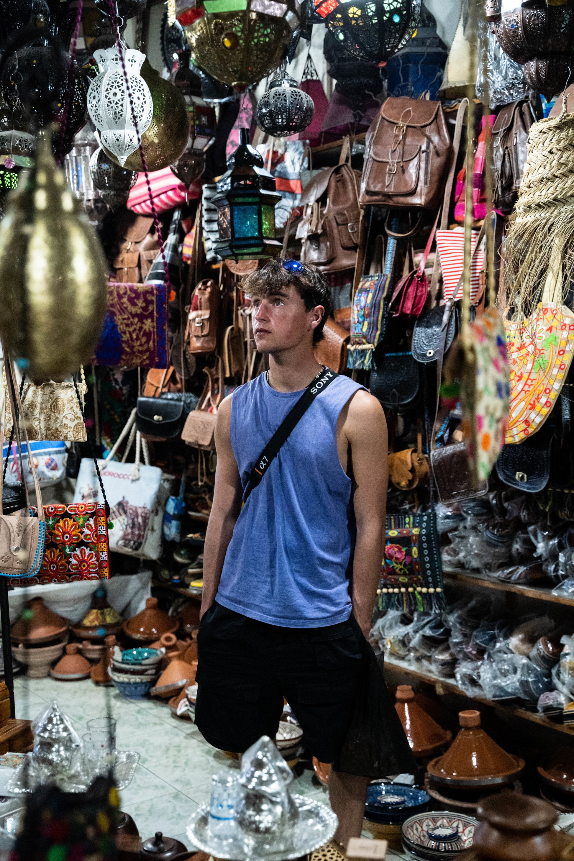 Trip participant standing in the middle of a store in morocco surrounded by bags and pots.