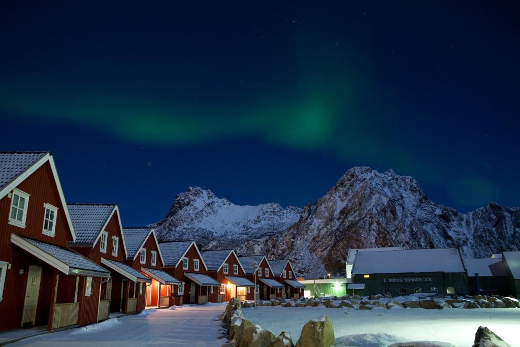 Red houses in a row in front of snowy mountains in Lofoten Norway.