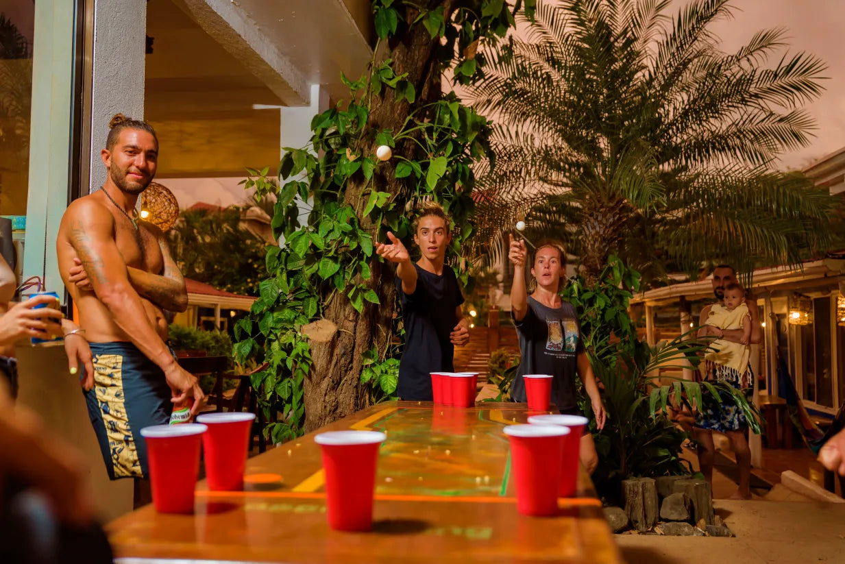 Small group trip participants playing beer pong at their hostel in Tamarindo.