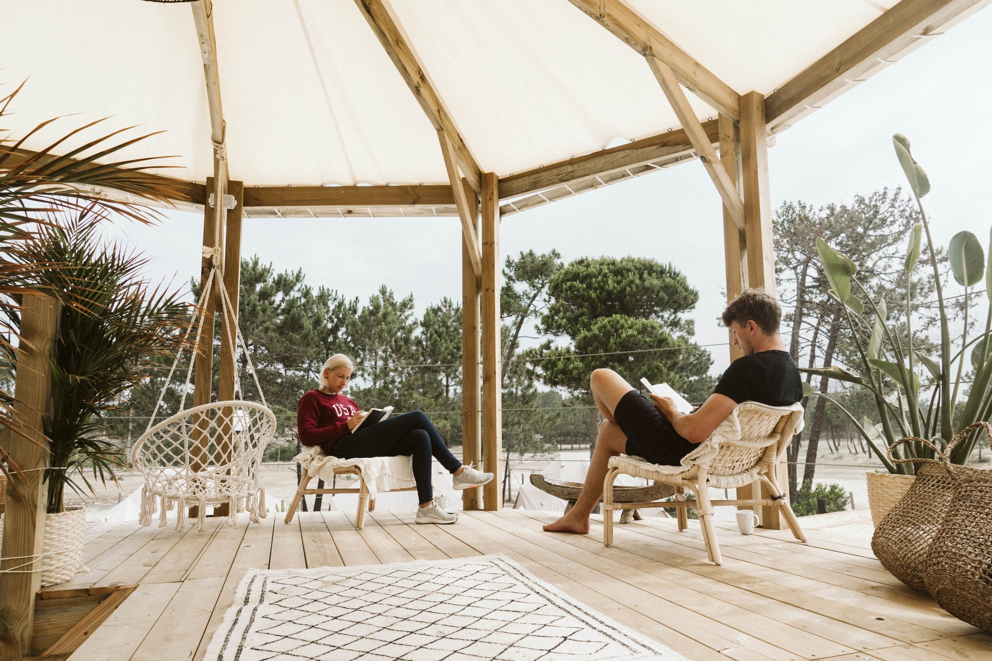 Two small group trip participants reading in the Dreamsea Surf Camp outdoor lounge area in Portugal.