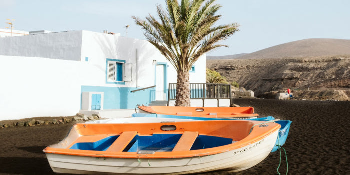 Small boats docked by a village and mountains in Fuerteventura Spain.