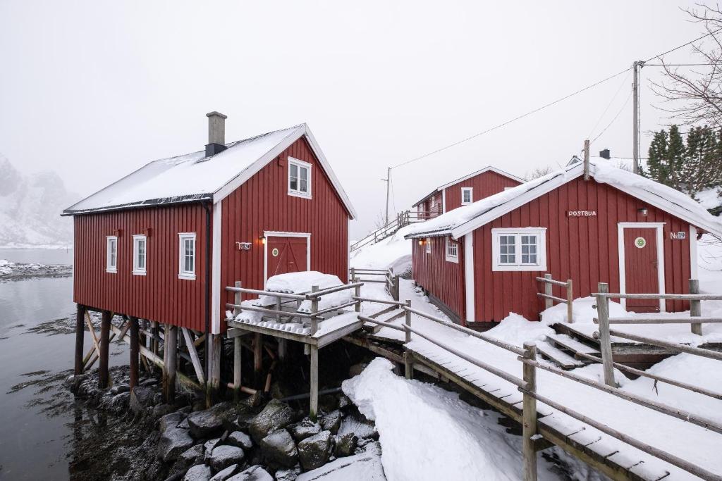 Red snow covered cabins on the lake in Lofoten Norway on a gloomy day.