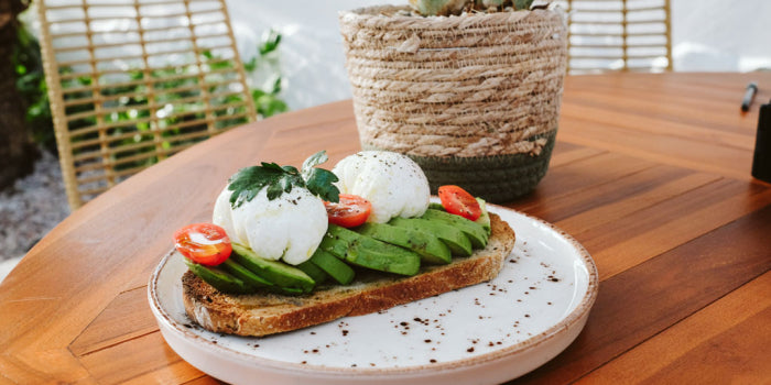 Toast with avocado mozzarella and tomatoes for breakfast on an outdoor dining table during a group trip.